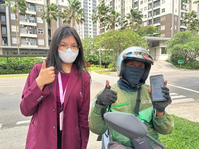 A student and an online driver giving thumbs up while showing the app on a phone